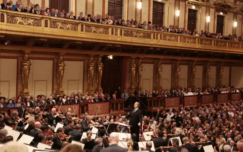 Un director dirige una orquesta sinfónica ante un público entusiasta, interpretando obras de Beethoven en un teatro majestuoso.