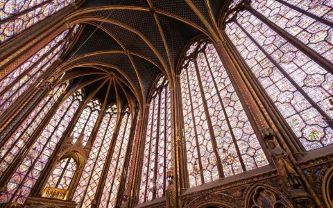 Interior de una capilla con vidrieras de colores y bóvedas ojivales, un ejemplo impresionante del estilo gótico.