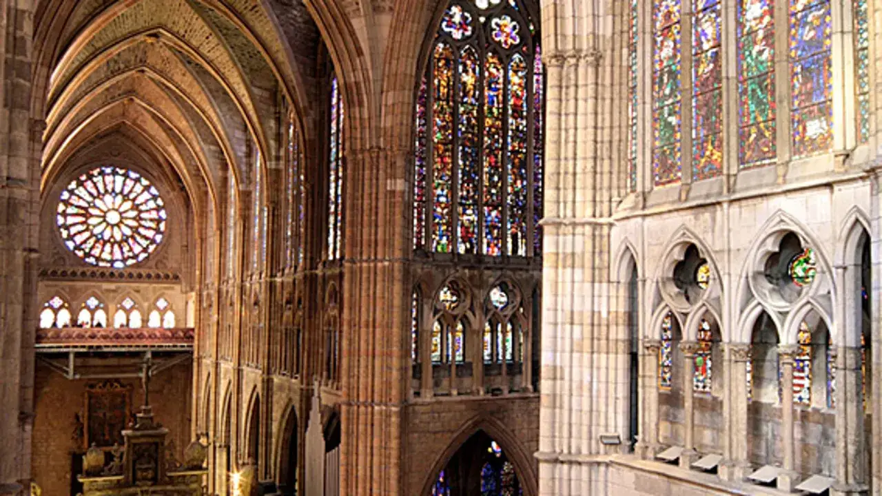 Interior de una catedral gótica con impresionantes vidrieras de colores y una gran roseta.