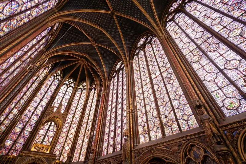 Interior de una capilla con vidrieras de colores y bóvedas ojivales, un ejemplo impresionante del estilo gótico.